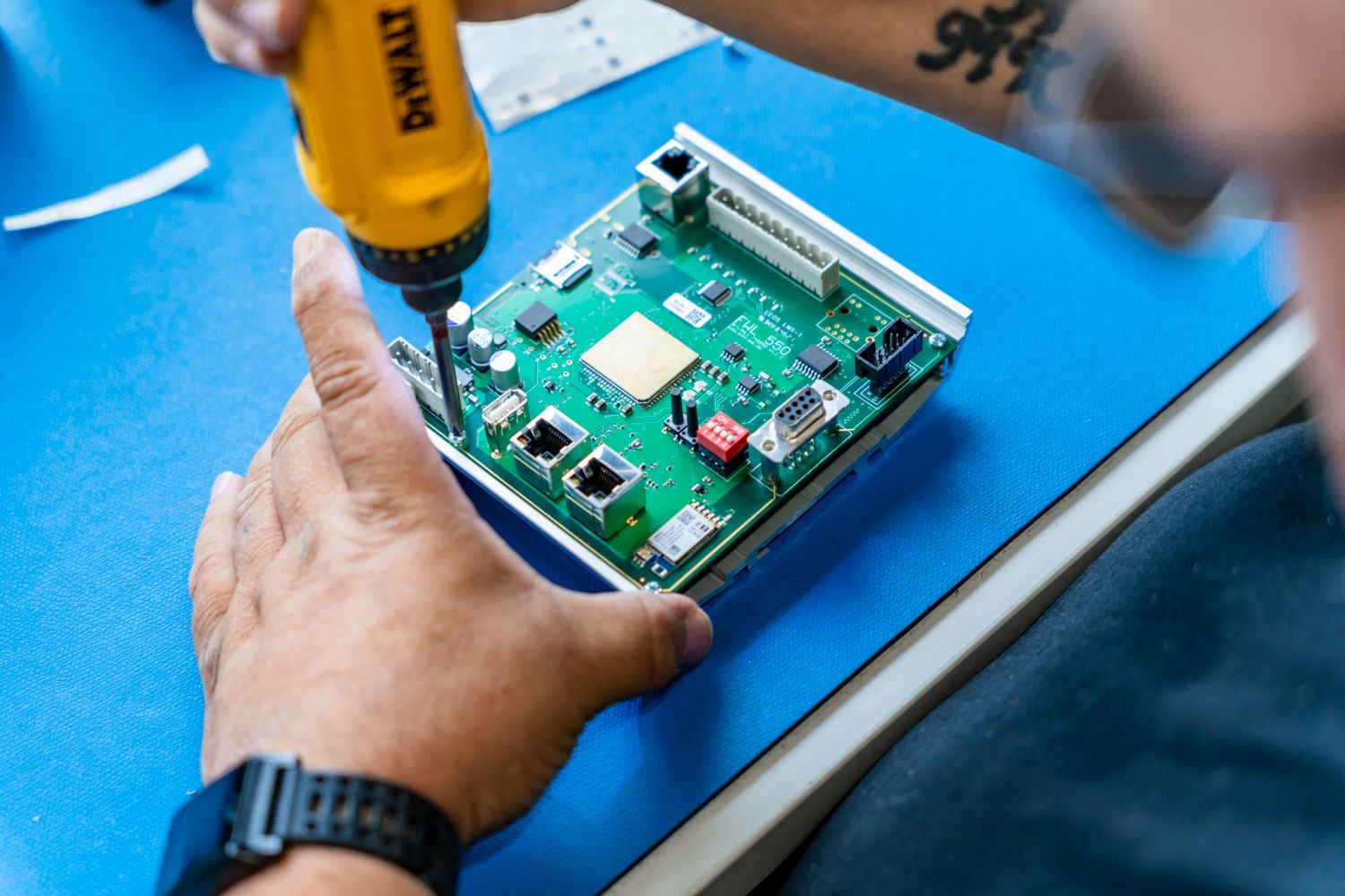 Manuelle Gerätemontage bei LEDtronix: Ein Mitarbeiter verschraubt eine bestückte Baugruppe im Alugehäuse.